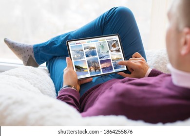 Hombre mirando hermosas fotos de invierno en una tableta en casa