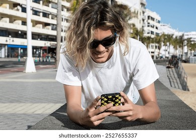 Man browsing his smartphone while lying on a road. Horizontal outdoors shot.