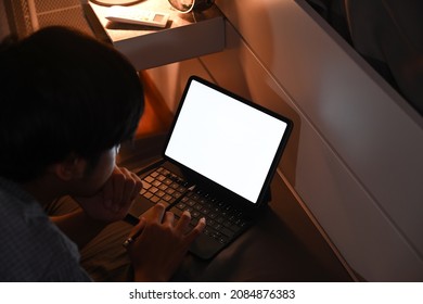Man browsing internet with computer table at night in bedroom.