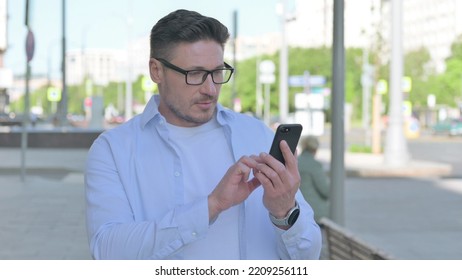 Man Browsing Internet On Smartphone Outdoor