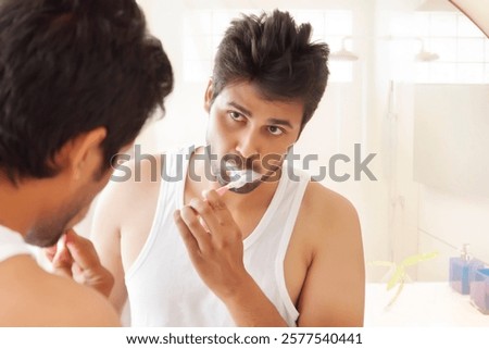 Man brushing teeth and looking at self in mirror