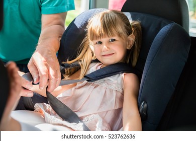 Man Buckling Seat Belt In Safety Seat In Car For Child