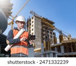 Man builder. Architect at construction site. Builder with tablet computer and papers. Man inspector checks quality of construction. Engineer near multi-story building under construction.