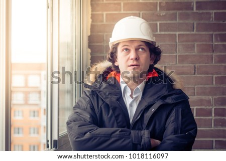 Man builder. Builder in protective clothing and helmet. Male builder. Portrait of mechanical worker. Engineer looking up. Copy space. Soft focus, toned.