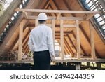 Man builder. Rear view of foreman with laptop. Contractor for construction company. Architect in unfinished building. Builder in wooden house under construction. Man engineer from construction team