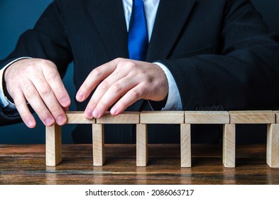 A man building a bridge of domino blocks. Strategy planning business expansion. Development and progression. Leadership. Create, design, expand a company. A stable foundation movement towards the goal