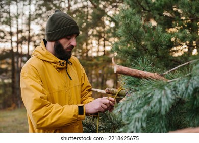 Man building a survival shelter in the forest. Shelter in the woods from pine branches. - Powered by Shutterstock