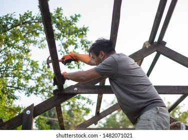 Man building wooden roof working with hammer