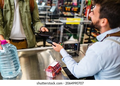 Man Buing Fresh Vegetables And Water At Grocery Store. Contactless Payment By Mobile Phone.