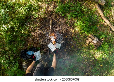 Man Burning Paper In A Campfire, Top View