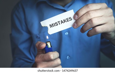 Man burning a piece paper with written Mistakes text. - Shutterstock ID 1474249637