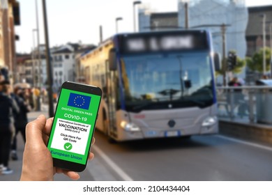 A man at a Bus Stop is holding smartphone with the European Union digital Green Pass for Covid-19 SARS-CoV-2. Safe travel concept during the Coronavirus pandemic and the Green Pass.