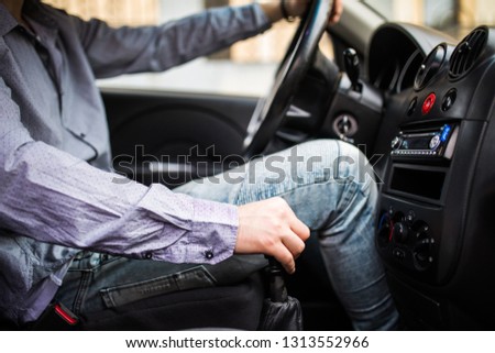 A man in a business suit in the car changes gear