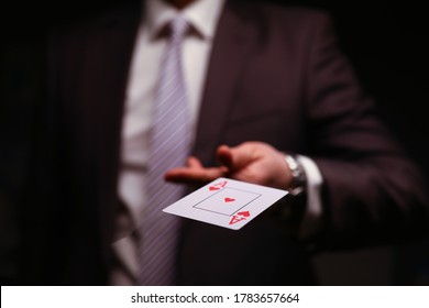 Man in business suit catche red ace playing card. Owning gambling business, maintaining casino and slot machine hall. Illusionist demonstrate trick.
