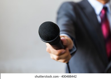 Man In Business Suit Holding A Microphone Conducting A Business Interview, Journalist Reporting, Public Speaking, Press Conference, MC