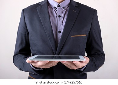 Man in business suit holding a tablet.
