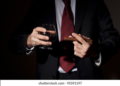 Man In A Business Suit Holds A Cigar And A Glass With Whisky