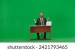 Man in business suit with horse head mask on studio green background. Businessman sits at desk, says something and points his hand to the sides. Concept of heavy office work.