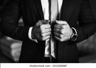 Man in business suit. A man puts on a suit. Close-up business stylish man buttoning his jacket. A businessman in an expensive suit.  Black and white photo