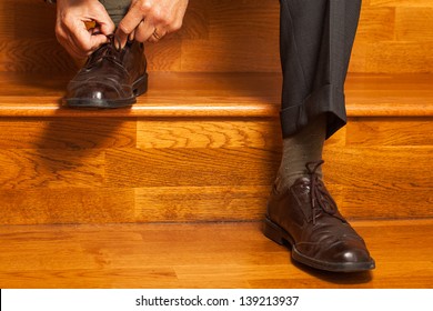 Man In A Business Suit Tying His Shoes