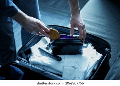 A man businessman collects things in a suitcase for a long business trip. Packing things before traveling