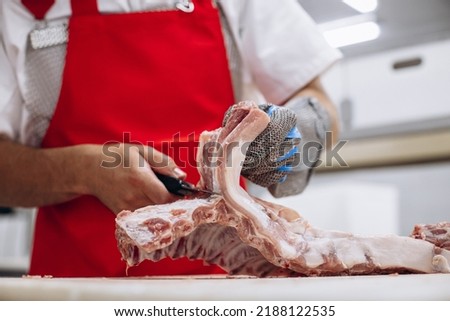 Man butcher at the freezer cutting meat