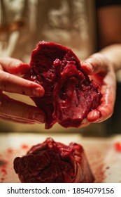 Man Butchering Fresh Venison Heart On Cutting Board