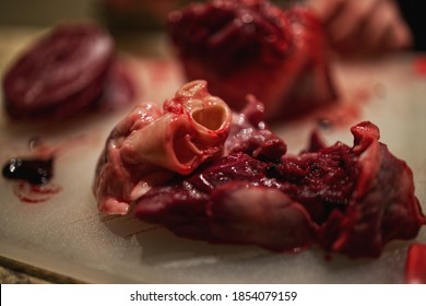 Man Butchering Fresh Venison Heart On Cutting Board