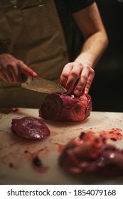 Man Butchering Fresh Venison Heart On Cutting Board