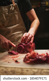 Man Butchering Fresh Venison Heart On Cutting Board