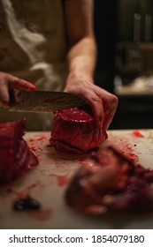 Man Butchering Fresh Venison Heart On Cutting Board