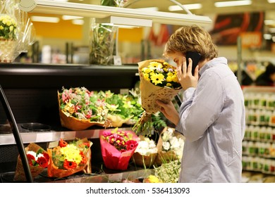 Man Buying Flowers At A Garden Center .Using Smarthone