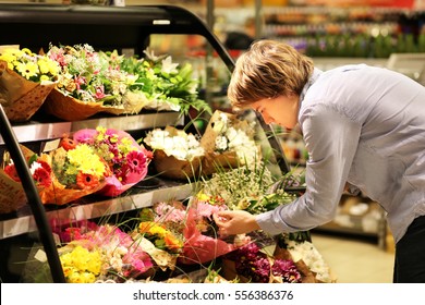 Man Buying Flowers At A Garden Center .Using Smarthone