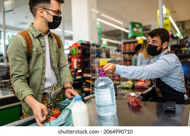 Man Is Buying Fresh Water, Vegetables And Fruits At Grocery Store. He And A Cashier Are Wearing Face Protective Masks Due To Covid-19 Pandemic.