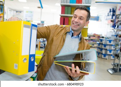 man buying stack of ringbinders