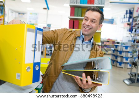 man buying stack of ringbinders
