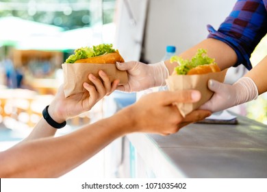 Man Buying Two Hot Dog In A Kiosk, Outdoors. Street Food. Close-up View.