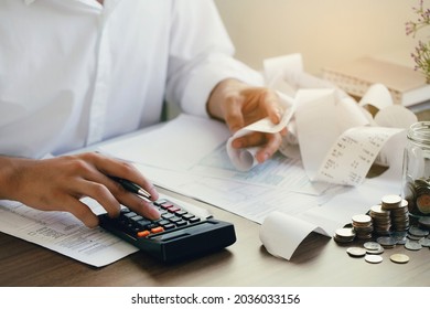 Man calculate domestic bills at home. Man using a calculator checking balance and costs at modern office.Business people doing paperwork for paying taxes.Expenses, account, taxes concept