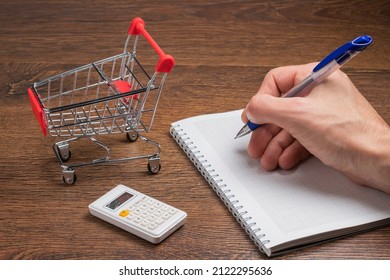 Man calculates the budget. Shopping cart a on table with calculator and paper. Budget of poor and low income family. Rising food and grocery store prices and expensive daily consumer goods concept