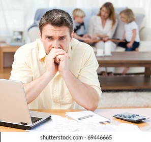 Man Calculating His Bills While His Family Are On The Sofa