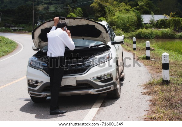 Man call for help on the phone.Are can\
not continue the way because of the broken\
car.