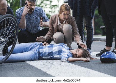 Man calling the emergency and woman bending over the accident casualty