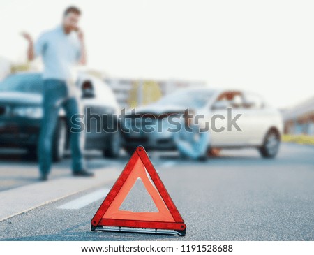 Man calling first aid after a bad car crash on the road,main focus on red triangle