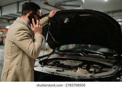Man calling for help with car breakdown, experiencing stress and unexpected problems in a garage setting with an open hood