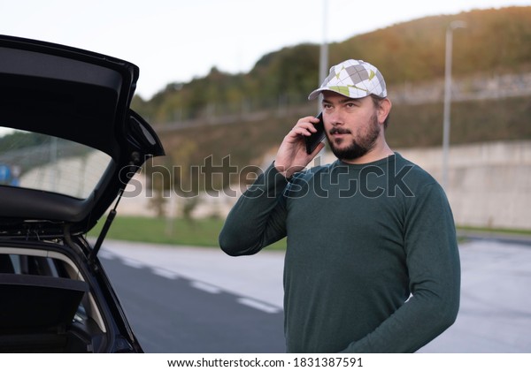 Man calling road assistance on the highway. Calling\
car service, assistance or  tow truck while having troubles with\
his car.