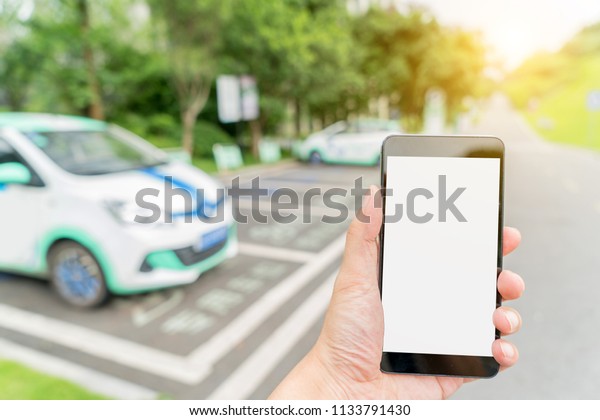 Man calls\
car with mobile phone APP in parking\
lot