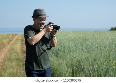 A man with a camera on the background of a wheat field. Concept: summer vacation.