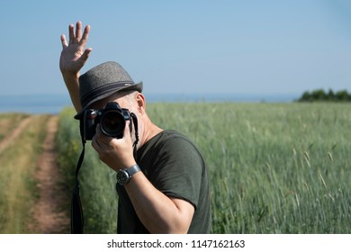 A man with a camera on the background of a wheat field. Concept: summer vacation.