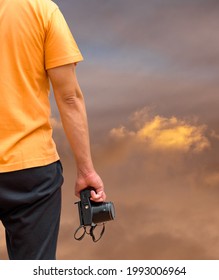 Man with camera. Rear view of a man with compact camera photographing the sky.