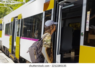 Man In Camouflage Clothing And Cap Boarding Train At Station.